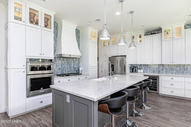 2800 Papeete Dr, Lake Havasu City, AZ 86404 - kitchen featuring custom exhaust hood, a sink, a kitchen island with sink, stainless steel appliances, and beverage cooler
