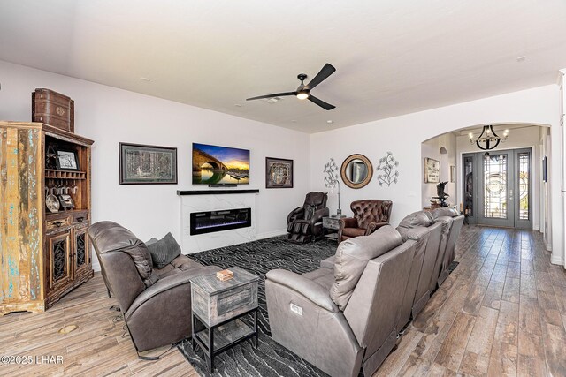 2800 Papeete Dr, Lake Havasu City, AZ 86404 - living room with ceiling fan with notable chandelier, arched walkways, a glass covered fireplace, light wood finished floors, and baseboards