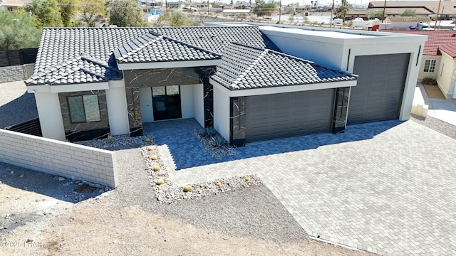 view of front of home featuring a garage, a tile roof, decorative driveway, and stucco siding