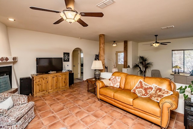 living room featuring arched walkways, light tile patterned floors, visible vents, and a ceiling fan