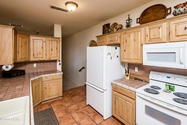 kitchen with tasteful backsplash, light brown cabinets, tile counters, white appliances, and visible vents