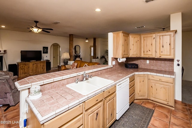 kitchen with a peninsula, dishwasher, a sink, open floor plan, and light brown cabinets