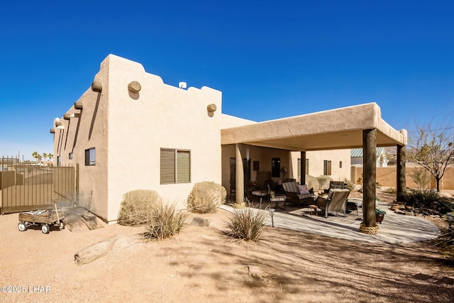 back of property with a patio, an outdoor hangout area, stucco siding, and fence