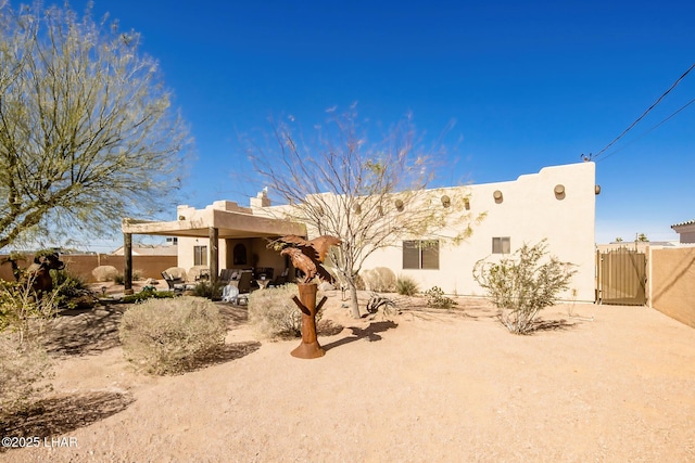 back of property with fence, a patio area, stucco siding, and a gate