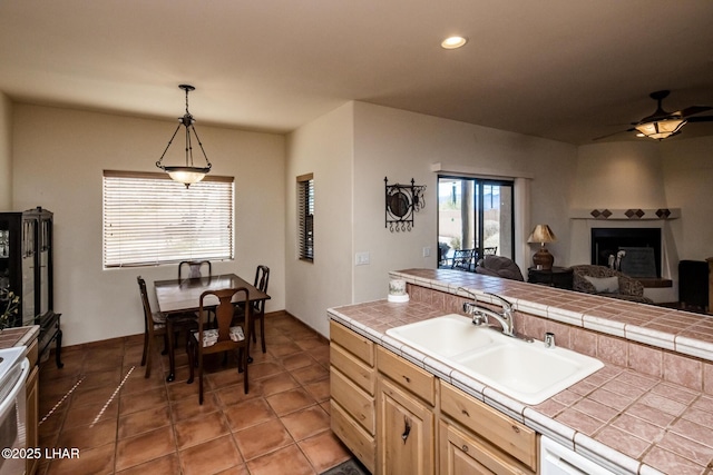 kitchen featuring tile countertops, tile patterned flooring, sink, ceiling fan, and pendant lighting