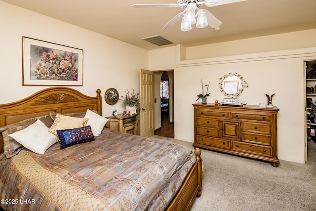 carpeted bedroom with arched walkways, visible vents, and a ceiling fan