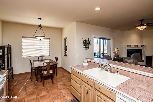 kitchen featuring ceiling fan, recessed lighting, a sink, open floor plan, and tile counters