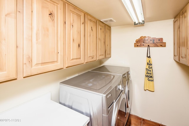 clothes washing area with separate washer and dryer, visible vents, and cabinet space