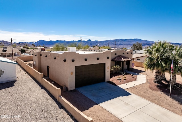 view of front facade with concrete driveway, stucco siding, a mountain view, an attached garage, and fence