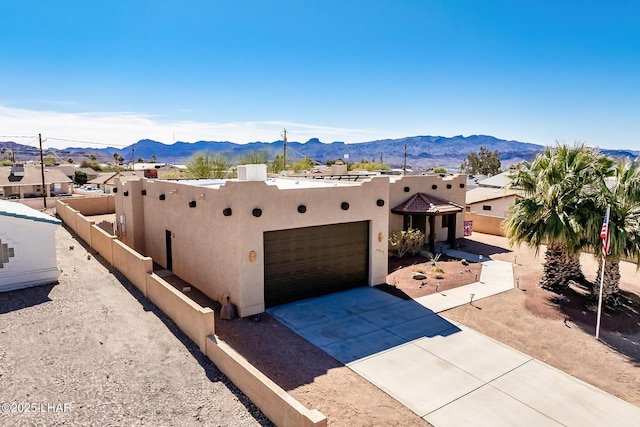 southwest-style home with stucco siding, a mountain view, driveway, a garage, and fence