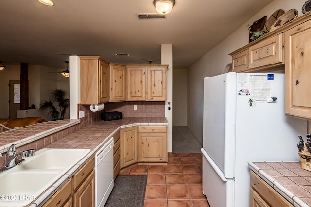 kitchen featuring sink, white appliances, tasteful backsplash, and tile counters