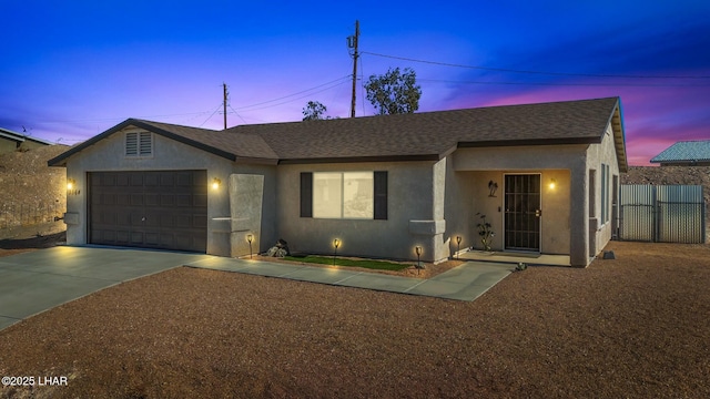 ranch-style home featuring concrete driveway, an attached garage, fence, and stucco siding