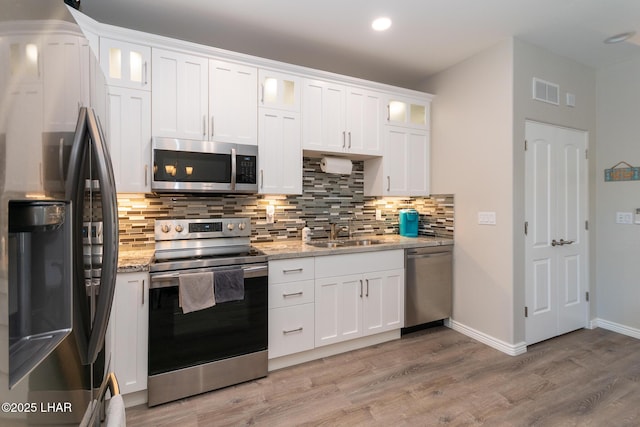 490 N Lake Havasu Ave Unit J, Lake Havasu City, AZ 86403 - kitchen featuring appliances with stainless steel finishes, a sink, light wood-style flooring, white cabinetry, and decorative backsplash