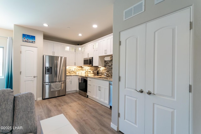 490 N Lake Havasu Ave Unit J, Lake Havasu City, AZ 86403 - kitchen with appliances with stainless steel finishes, tasteful backsplash, light wood-style floors, white cabinetry, and recessed lighting