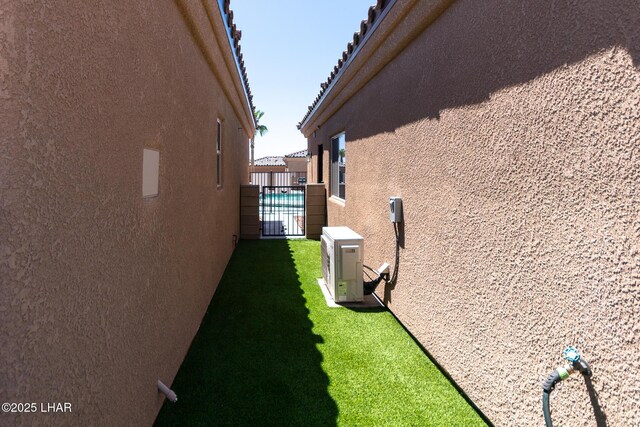 490 N Lake Havasu Ave Unit J, Lake Havasu City, AZ 86403 - view of side of home featuring stucco siding, a cooling unit, fence, and a gate