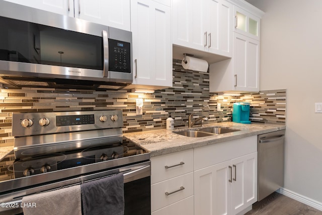 490 N Lake Havasu Ave Unit J, Lake Havasu City, AZ 86403 - kitchen with appliances with stainless steel finishes, white cabinets, a sink, tasteful backsplash, and light stone counters