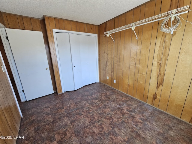 unfurnished bedroom featuring a textured ceiling and wooden walls