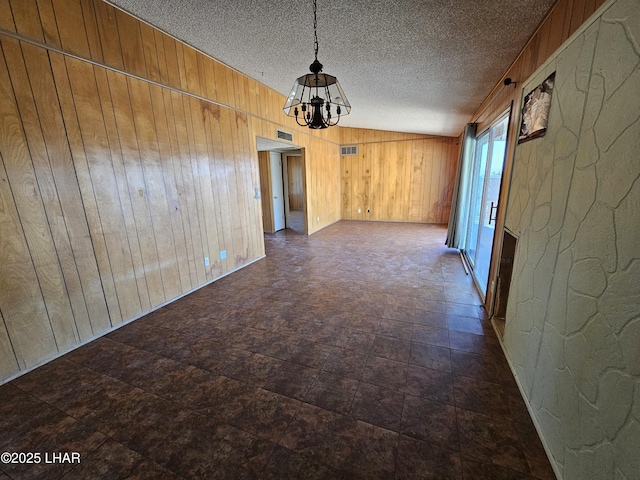 empty room with wooden walls and a textured ceiling