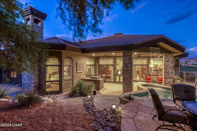 back house at dusk featuring ceiling fan and a patio area