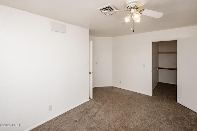 unfurnished bedroom featuring a walk in closet, carpet, visible vents, and a ceiling fan