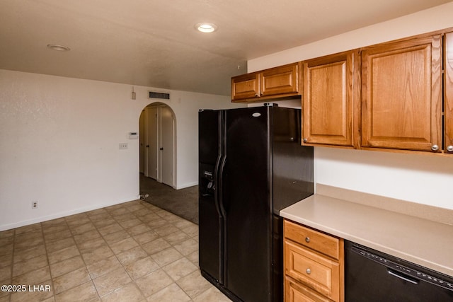 kitchen featuring brown cabinetry, visible vents, arched walkways, black appliances, and light countertops