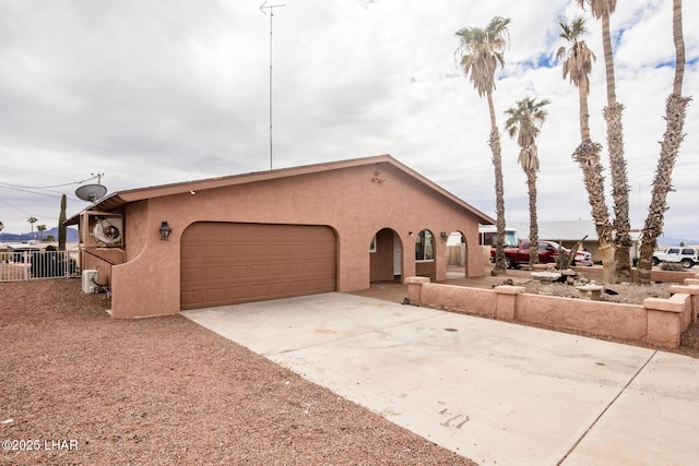 view of front of property featuring stucco siding, concrete driveway, a garage, and fence