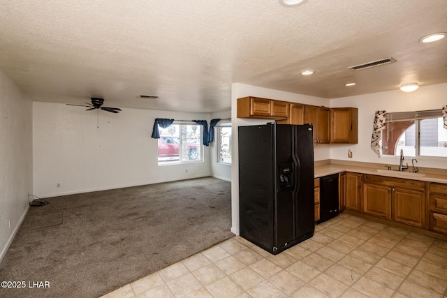 kitchen with visible vents, light colored carpet, black appliances, and a sink