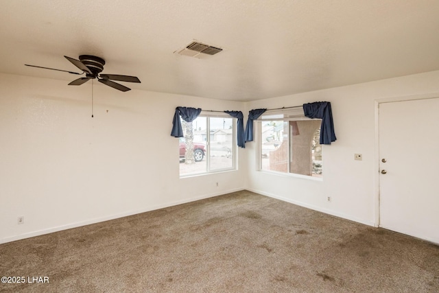 empty room with visible vents, baseboards, carpet, and a ceiling fan