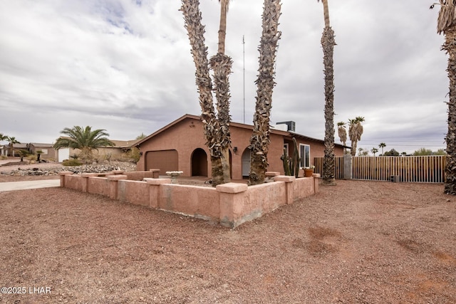 exterior space featuring stucco siding, an attached garage, and fence