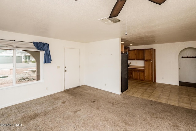 unfurnished living room with a textured ceiling, visible vents, and light carpet