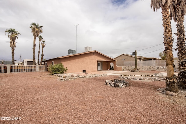 view of side of home with stucco siding, cooling unit, and fence