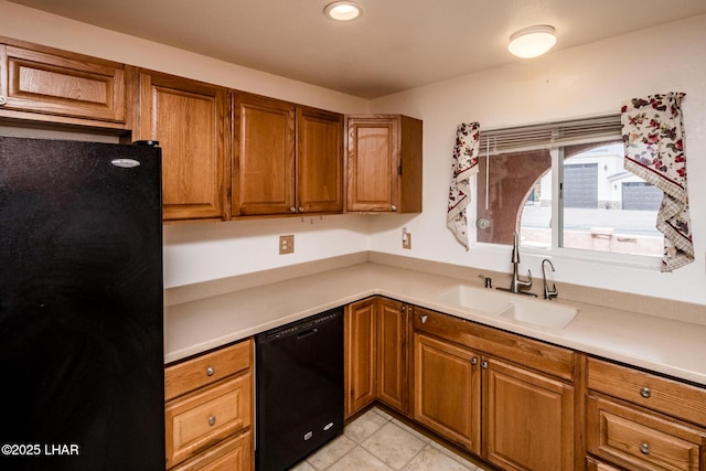 kitchen featuring brown cabinets, black appliances, light countertops, and a sink