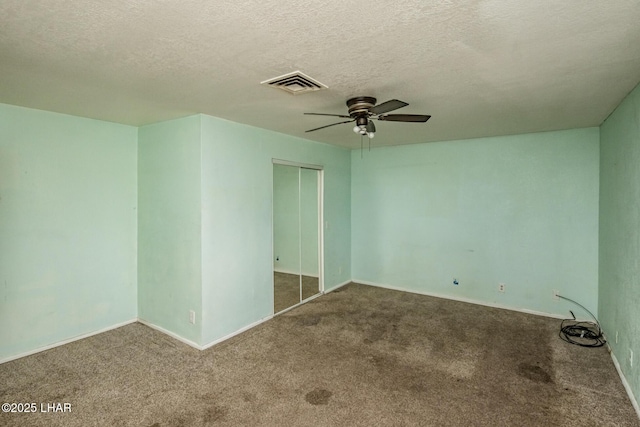 carpeted empty room with visible vents, baseboards, a textured ceiling, and ceiling fan