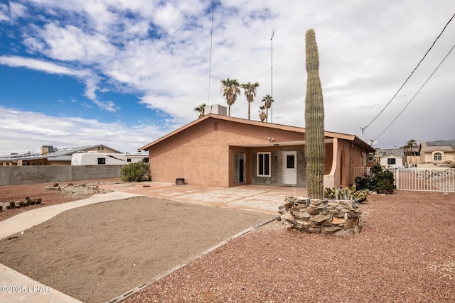 rear view of house with stucco siding, a patio, and a fenced backyard