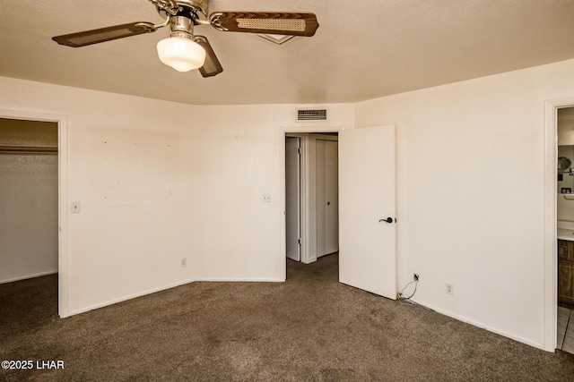 unfurnished bedroom with visible vents, a ceiling fan, dark carpet, connected bathroom, and baseboards