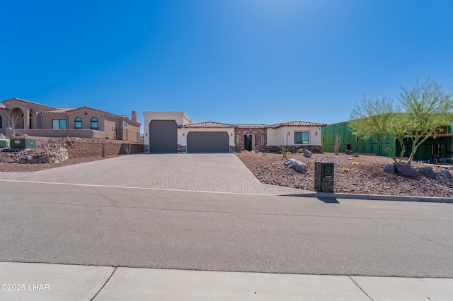 view of front of property featuring a tile roof, stucco siding, decorative driveway, a garage, and stone siding