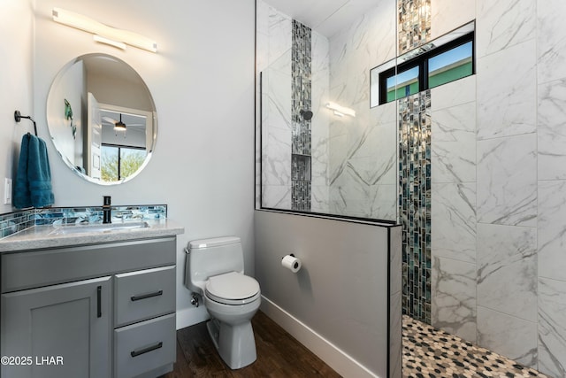 bathroom featuring toilet, a ceiling fan, a walk in shower, wood finished floors, and vanity