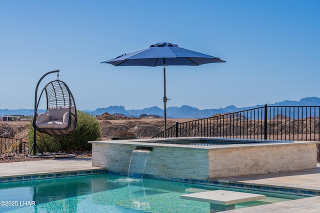 view of swimming pool with a jacuzzi, fence, and a mountain view