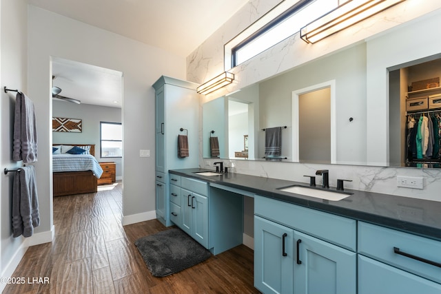 bathroom featuring double vanity, connected bathroom, wood finished floors, and a sink