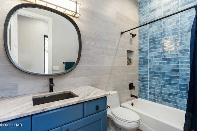 bathroom with vanity, tile walls, toilet, and washtub / shower combination