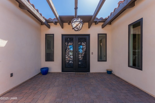 entrance to property with french doors, a patio area, stucco siding, and a tiled roof