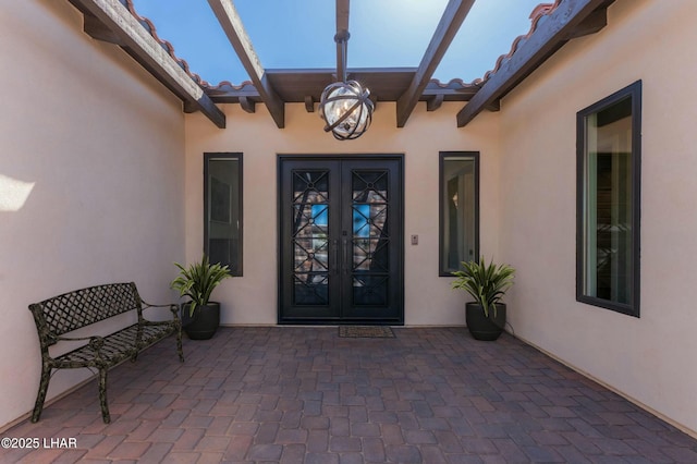 entrance to property with stucco siding, a tiled roof, and french doors