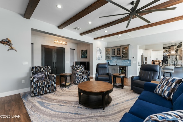 living area featuring wood finished floors, baseboards, beam ceiling, wine cooler, and ceiling fan with notable chandelier