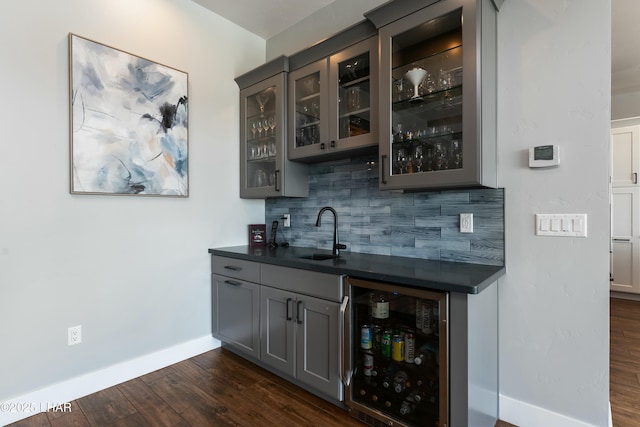 bar featuring decorative backsplash, a sink, wine cooler, indoor wet bar, and dark wood-style flooring