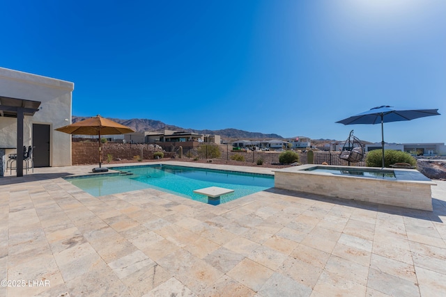 view of swimming pool featuring a patio, a mountain view, a fenced in pool, and an in ground hot tub