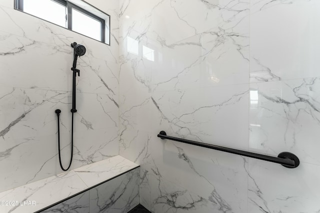 full bathroom with a marble finish shower and stone wall