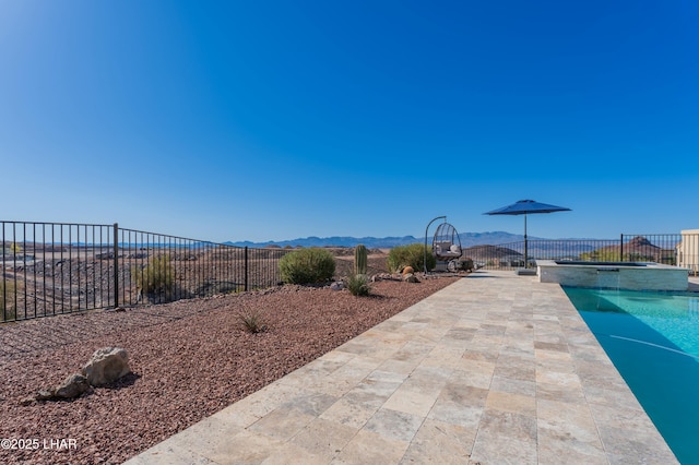 exterior space with a mountain view, a pool with connected hot tub, and fence