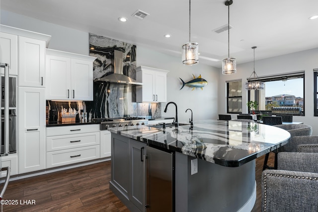 kitchen featuring visible vents, beverage cooler, appliances with stainless steel finishes, and wall chimney exhaust hood