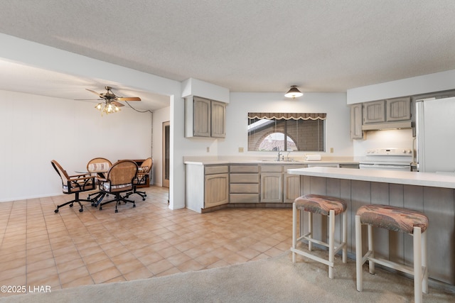 kitchen with sink, ceiling fan, a kitchen breakfast bar, white electric range oven, and a textured ceiling