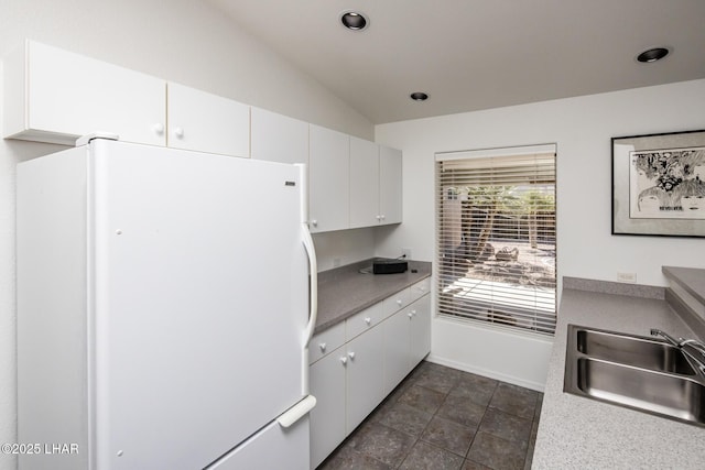 kitchen featuring lofted ceiling, recessed lighting, a sink, white cabinets, and freestanding refrigerator